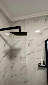 a bathroom with a glass shower with white marble walls at Stylish Executive Apartment with Power Backup in Johannesburg