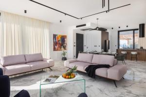 ein Wohnzimmer mit 2 rosa Sofas und einer Küche in der Unterkunft Luxury Villa Ole with Pool in Kostrena