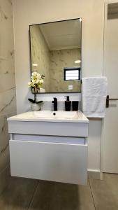 a bathroom with a white sink and a mirror at Stylish Executive Apartment with Power Backup in Johannesburg