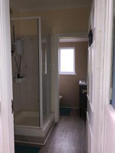 a bathroom with a shower and a toilet and a window at Rectory Cottage in Croydon