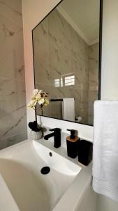uma casa de banho branca com um lavatório e um espelho em Stylish Executive Apartment with Power Backup em Joanesburgo