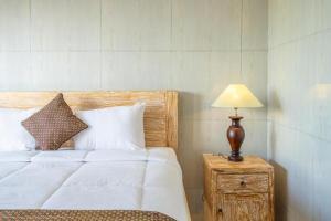 een slaapkamer met een bed en een lamp op een nachtkastje bij Pondok Lulik Seseh Beach in Munggu