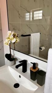 a bathroom sink with a mirror and a vase with flowers at Stylish Executive Apartment with Power Backup in Johannesburg
