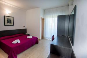 una camera con letto rosso e frigorifero di Hotel Union a Riccione