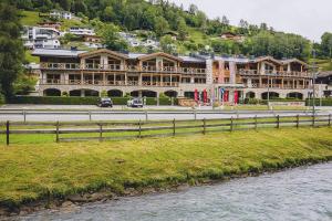 duży budynek przy drodze obok rzeki w obiekcie AvenidA Mountain Lodges Kaprun w Kaprunie