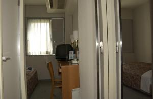 Habitación con cama y escritorio con TV. en Himeji Green Hotel Tatemachi, en Himeji