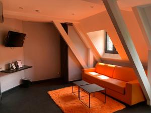 a living room with an orange couch and a tv at Moulin de Cambelong- Emilie & Thomas in Conques-en-Rouergue