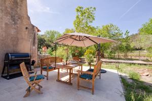 un patio con mesa, sillas y sombrilla en Le Mas de Georges - Jolie maison avec piscine privée, en Le Thoronet