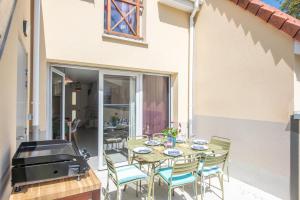eine Terrasse mit einem Tisch, Stühlen und einem Grill in der Unterkunft Bibifoc Baie - au coeur de la Baie de la Somme in Saint-Valery-sur-Somme