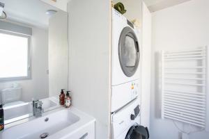 La salle de bains blanche est pourvue d'un lavabo et d'un lave-linge. dans l'établissement Bibifoc Baie - au coeur de la Baie de la Somme, à Saint-Valery-sur-Somme