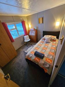 1 dormitorio con cama, escritorio y ventana en Cozy rural lodge, amazing views close to Holmfirth, en Holmfirth