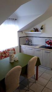 a kitchen with a green table and two chairs at Apartmani Kalinic in Bijela