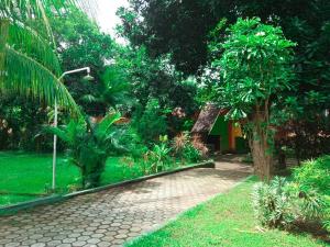 a garden with a brick path and trees and a street light at Votel Manyar Resort Banyuwangi in Ketapang