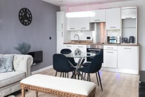 Central Leeds Penthouse في ليدز: مطبخ وغرفة معيشة مع طاولة وكراسي