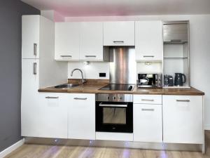 Una cocina con gabinetes blancos y un fregadero. en Central Leeds Penthouse, en Leeds 14 fotos más
