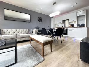 Central Leeds Penthouse في ليدز: غرفة معيشة مع أريكة وطاولة وكراسي
