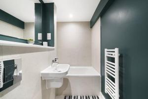 a bathroom with a white sink and green cabinets at Skygardens - Stylish Central Duplex - Roof Garden in Manchester