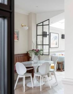 a white dining room with a table and white chairs at ALTIDO Spectacular house with private garden in London