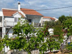 Ein weißes Haus mit einem Zaun und einem Haufen Trauben in der Unterkunft Apartement ANCICA in Split