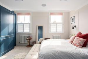 a bedroom with a large bed and two windows at ALTIDO Spectacular house with private garden in London