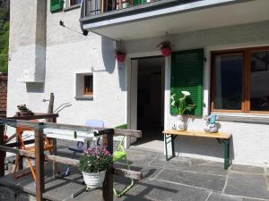 a patio with a table and a green door at Casa Allegra- appartamento Calla in Cavergno