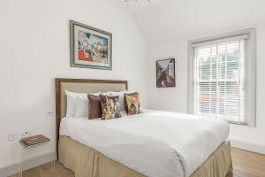 a white bedroom with a large bed with pillows at Veeve - Heart of Hampstead in London