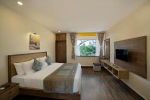 1 dormitorio con 1 cama grande y TV en Sterling Karwar, en Kārwār