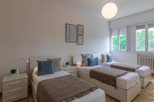 2 camas en una habitación con paredes y ventanas blancas en Fiera di Ferrara Huge Apartment x7! en Ferrara