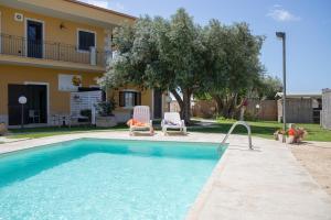 a pool with two chairs and a house at La Lantana in Marina di Ragusa