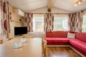 ein Wohnzimmer mit einem roten Sofa und einem Tisch in der Unterkunft Mobil Home dans camping Frejus in Fréjus