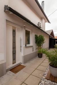une maison blanche avec une porte et des plantes devant elle dans l'établissement Ljubljana studio with FREE parking, Washer & Dryer, à Ljubljana