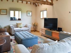 a living room with a couch and a tv at The Cow Shed in Hooe