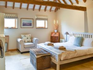 a bedroom with a bed and a chair and windows at The Cow Shed in Hooe