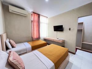 Cette chambre comprend deux lits et une télévision. dans l'établissement Hotel Winotosastro by Athelu, à Timuran