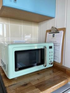a microwave sitting on top of a kitchen counter at Reef Shepherds Hut in Penally
