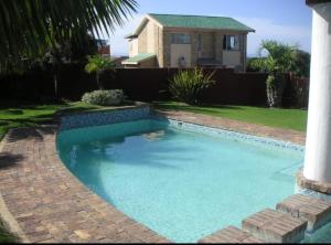 a swimming pool in a yard with a house at OCEAN VIEW, DOLPHIN BAY 19 ASTON BAY in Jeffreys Bay