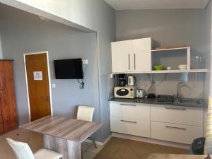 a kitchen with white cabinets and a wooden table at Sacha Tourist Residence 1 in Mahébourg