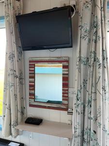 a flat screen tv on a wall with a window at Reef Shepherds Hut in Penally