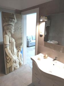 a bathroom with a sink and a carving of a woman at Attalos luxury flat Psyrri square in Athens