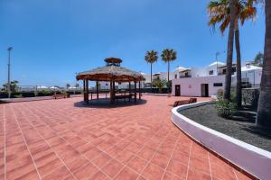 einen Pavillon mit Bänken und Palmen auf einer Terrasse in der Unterkunft Casa Yare, shared pool, air-con, fast wifi in Costa Teguise