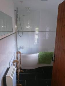 a white bath tub in a bathroom with a green towel at Gors Eilian in Amlwch