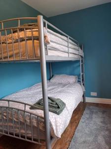 1 dormitorio con 2 literas y pared azul en Cosy cottage near Alton Towers, en Rocester