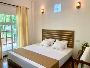 - une chambre avec un lit doté de draps blancs et une fenêtre dans l'établissement Imperial Resort, à Uda Walawe