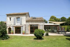 ein großes Steinhaus mit Rasen davor in der Unterkunft Superbe Mas contemporain au pied du Luberon in Cheval-Blanc