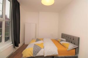 ein Schlafzimmer mit einem Bett mit einer Decke und Kissen in der Unterkunft Ideal 2 Bed Flat close to City in London