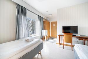 a hotel room with a bed and a desk and a television at Hotelli Uninen Kotka in Kotka