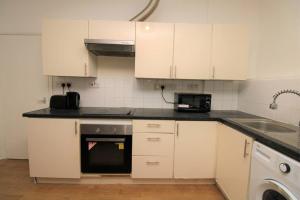 cocina con armarios blancos, fregadero y lavavajillas en Ideal 2 Bed Flat close to City, en Londres