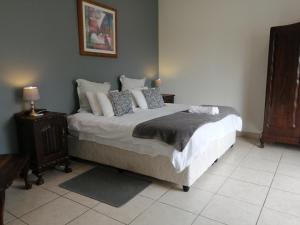 a bedroom with a large bed with pillows at Serendipity Country House in Amanzimtoti
