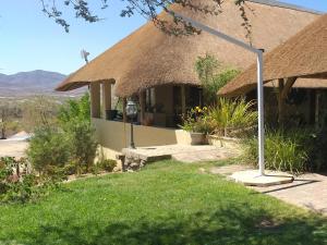 a house with a thatch roof and a grass at Uitkyk Guest Farm in Usakos