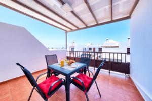 een tafel en stoelen op een balkon met uitzicht op de oceaan bij Casa Yare, shared pool, air-con, fast wifi in Costa Teguise